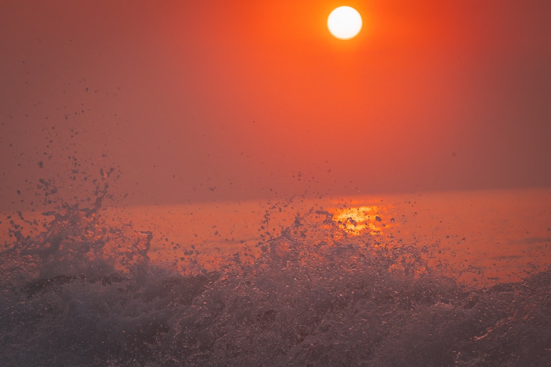 A bright sun sets over the ocean waves.