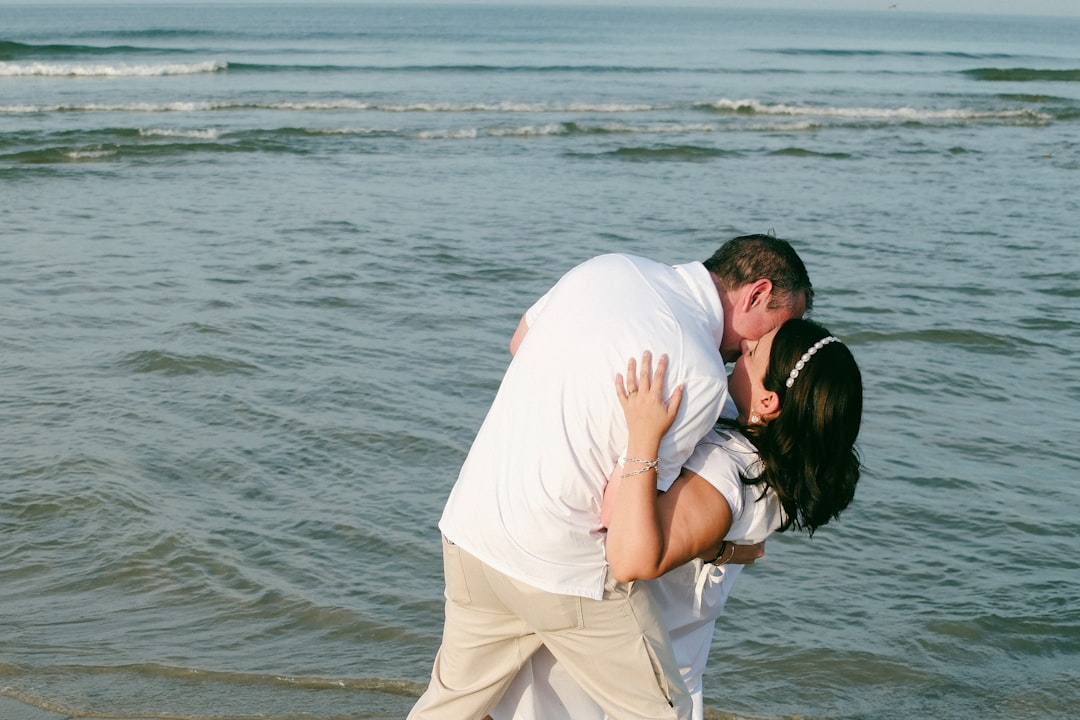 Couple kissing on the beach with ocean waves.